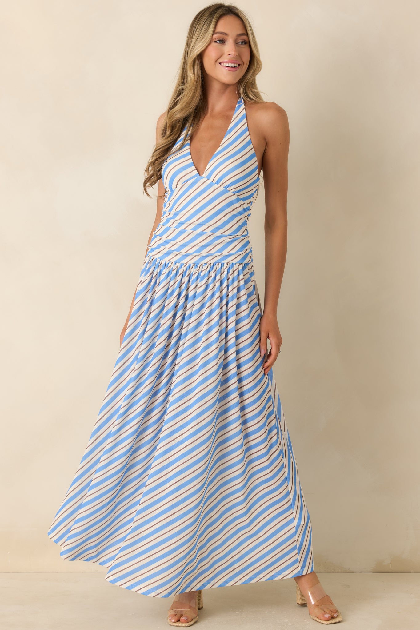 Feminine striped maxi dress showcasing a fitted waist, halter neckline, and airy, lightweight construction.