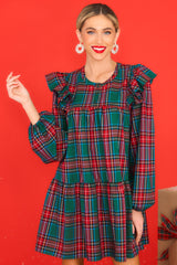 Front view of this dress that features a round neckline, three functional buttons down the front, ruffle detailing on the shoulders, long sleeves with elastic cuffs, and a babydoll silhouette.