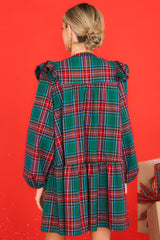 Back view of this dress that features a round neckline, three functional buttons down the front, ruffle detailing on the shoulders, long sleeves with elastic cuffs, and a babydoll silhouette.