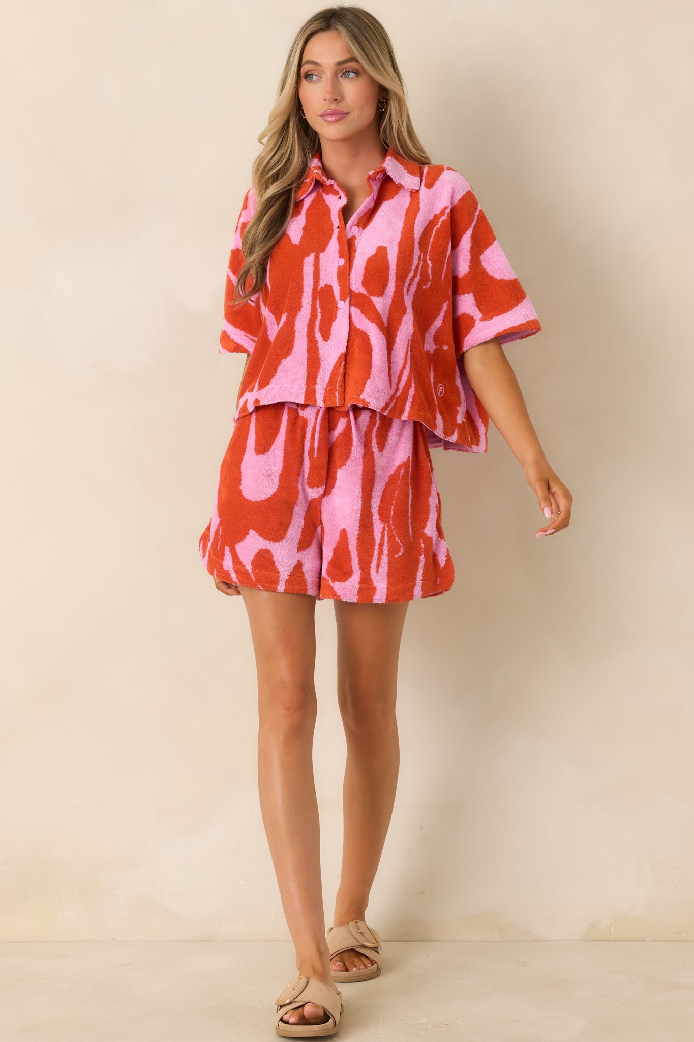 Bold floral print top with short sleeves, structured collar, and relaxed cropped fit in textured fabric.