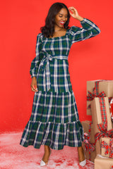 Full body view of this dress that features a square neckline, long sleeves with elastic cuffs, a fully smocked bust section, a self-tie belt at the waist, and a long, flowy skirt.