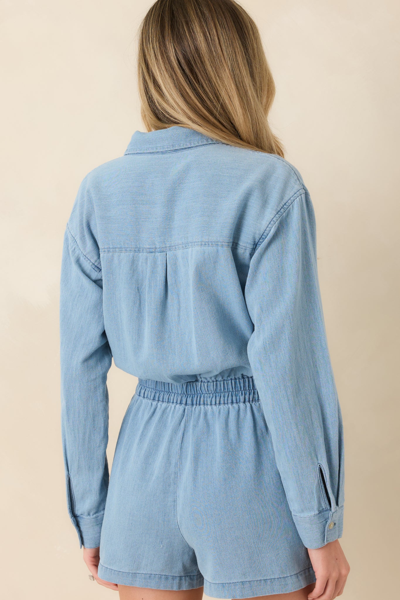 Rear view of lake blue romper with long sleeves and elasticized waist shaping.