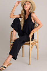 This black jumpsuit features a v-neckline, a lightweight material, a wide leg, and a slightly cropped hemline.
