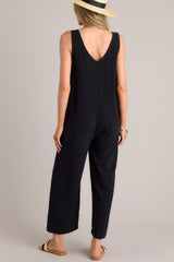 Back view of this black jumpsuit that features a v-neckline, a lightweight material, a wide leg, and a slightly cropped hemline.