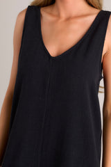Close up view of this black jumpsuit that features a v-neckline, a lightweight material, a wide leg, and a slightly cropped hemline.