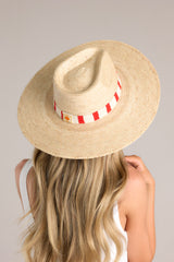 Full view of this hat that features a woven striped band, and is handmade with palm fronds.