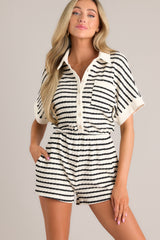 Front view of this stripe romper that features a collared neckline, a functional button front, a breast pocket, wide short sleeves, an elastic waistband, functional hip pockets, and a textured material.