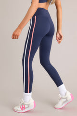 Side view of these leggings that feature a high waisted design, thick waistband, a pocket in the back of the waistband, and colored stripes down the legs.