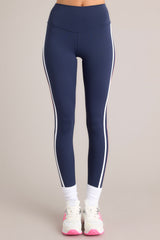 Front view of these leggings that feature a high waisted design, thick waistband, a pocket in the back of the waistband, and colored stripes down the legs.