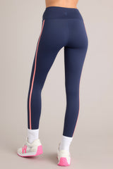 Back view of these leggings that feature a high waisted design, thick waistband, a pocket in the back of the waistband, and colored stripes down the legs.