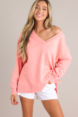 This pink sweatshirt features a v-neckline, a soft material, a split hemline, and ribbed cuffed sleeves.