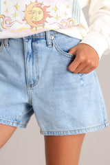 Close up view of these denim shorts that feature a high waist, classic button-zipper closure, functional belt loops, and five pockets.
