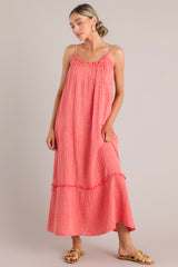 Front view of this coral midi dress that features a gauze cotton fabric, adjustable straps, and a tiered skirt.