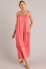 Movement shot of this coral midi dress that features a gauze cotton fabric, adjustable straps, and a tiered skirt.