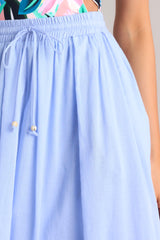 Close up view of this skirt that features a high waisted design, an elastic waistband, a self-tie drawstring, functional pockets, flowing fabric, and a thick hemline.