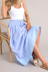 This blue skirt features a high waisted design, an elastic waistband, a self-tie drawstring, functional pockets, flowing fabric, and a thick hemline.