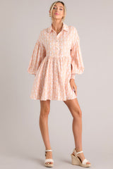 Full body view of this dress that features a collared neckline, functional buttons down the front, long sleeves with smocked cuffs, and a flowy, relaxed fit throughout.