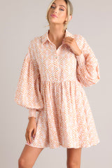 Front view of this dress that features a collared neckline, functional buttons down the front, long sleeves with smocked cuffs, and a flowy, relaxed fit throughout.