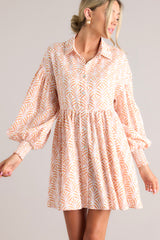 Full front view of this dress that features a collared neckline, functional buttons down the front, long sleeves with smocked cuffs, and a flowy, relaxed fit throughout.