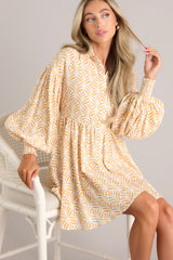 Close up view of this dress that features a collared neckline, functional buttons down the front, long sleeves with smocked cuffs, and a flowy, relaxed fit throughout.