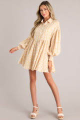 Full body view of this dress that features a collared neckline, functional buttons down the front, long sleeves with smocked cuffs, and a flowy, relaxed fit throughout.
