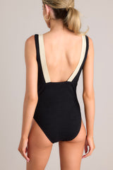 Back view of this one piece that features a v-neckline, a gold accent ring, shimmer detailing, a textured material, an open back, and a full coverage backside.