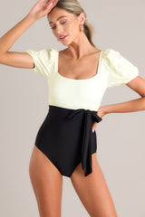 Front view of  this one piece that features a square neckline, removable padding, a color block design, a self-tie waist, elastic cuffed short sleeves, and a full coverage backside.