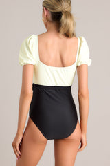Back view of  this one piece that features a square neckline, removable padding, a color block design, a self-tie waist, elastic cuffed short sleeves, and a full coverage backside.