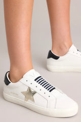 These black, white, and gold sneakers feature a rounded toe, a laceless design, a comfortable fit, and a star detail.