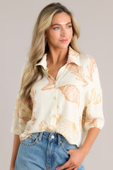 Front view of this ivory top featuring a collared neckline, a seashell print on lightweight fabric, and a slightly cropped length.