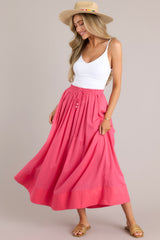 This pink skirt features a high waisted design, an elastic waistband, a self-tie drawstring, functional pockets, flowing fabric, and a thick hemline.