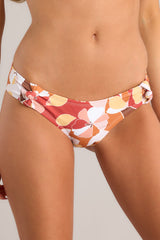 Close up view of floral patterned bottoms feature non adjustable knots on each hip, a peach floral print, and a classic low rise bikini style.