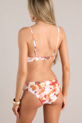 Back view of loral patterned bottoms feature non adjustable knots on each hip, a peach floral print, and a classic low rise bikini style.