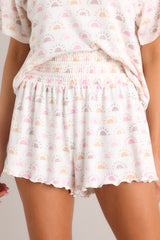 These white shorts feature an smocked elastic waistband, lettuce hemline, and lightweight sun print.