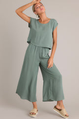 These green pants feature a high waisted design, an elastic waistband, functional hip pockets, a wide leg design, and a slightly cropped length.