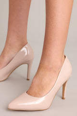 Close up side view of these beige heels with a pointed toe, vibrant color, glossy finish, and skinny heel.