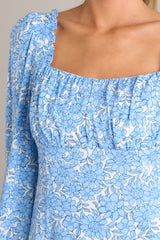 Close up view of this dress that features a square neckline, ruching in the bust, a smocked back insert, a discrete side zipper, and elastic cuffed long sleeves.