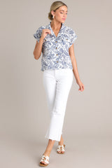 This blue and white top features a collared v-neckline, functional button front design, breast pockets, and dolman sleeves.
