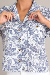 Close up view of this top that features a collared v-neckline, functional button front design, breast pockets, and dolman sleeves.