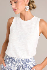 This white top features a high round neckline, a sleeveless design, a high back, ribbed texture around the hemlines, and a light breathable fabric.