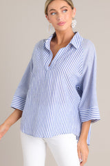 Angled view of this collared top that features a v-neckline, three-quarter length sleeves, and a subtle pleat in the back.