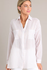 Front view of this beige top that features a collared neckline, buttons down the front, two pockets at the bust, buttoned cuffs, and a lightweight material.