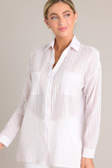 Angled front view of this beige top that features a collared neckline, buttons down the front, two pockets at the bust, buttoned cuffs, and a lightweight material.