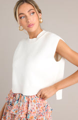 This white top features a ribbed crew neckline, a knitted fabric, a sleeveless design, a cropped length, and a split hemline.