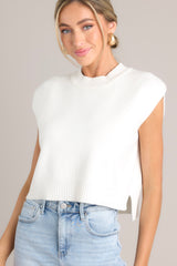 Front view of this top that features a ribbed crew neckline, a knitted fabric, a sleeveless design, a cropped length, and a split hemline.