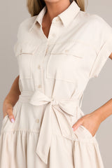 Close up view of this dress that features a collared neckline, functional breast pockets, a button front, a self-tie belt, belt loops, functional hip pockets, a single tier, and cuffed short sleeves.