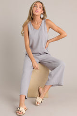 This grey jumpsuit features a v-neckline, a lightweight material, a wide leg, and a slightly cropped hemline.