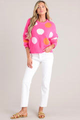 Full view of this hot pink polka dot sweater featuring a crew neckline, dropped shoulders, a ribbed hemline and ribbed cuffed long sleeves.