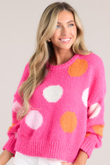Close up of the hot pink polka sweater with a ribbed hem and cuffs, and a crew neckline.