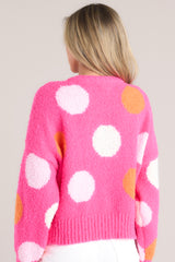 Back view of this hot pink polka dot sweater featuring a crew neckline, dropped shoulders, a ribbed hemline and ribbed cuffed long sleeves.